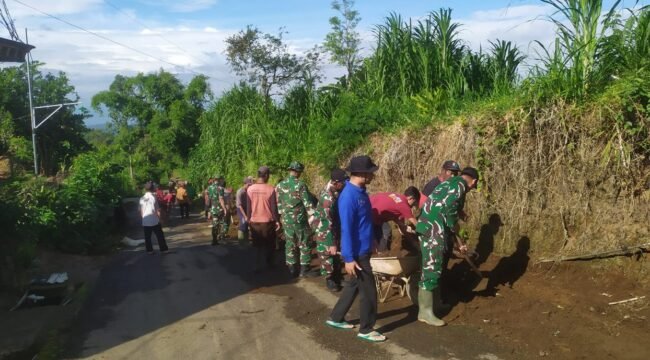 Foto: Personel TNI dari Koramil 0806-04/Bendungan bersama warga Desa Masaran bergotong royong membersihkan saluran air dan material tanah di tepi jalan desa, Kecamatan Bendungan, Kabupaten Trenggalek, Jumat (16/1/2026)